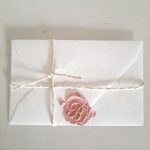 Sigillo rosa su busta bianca- simbolo di comunicazione elegante.