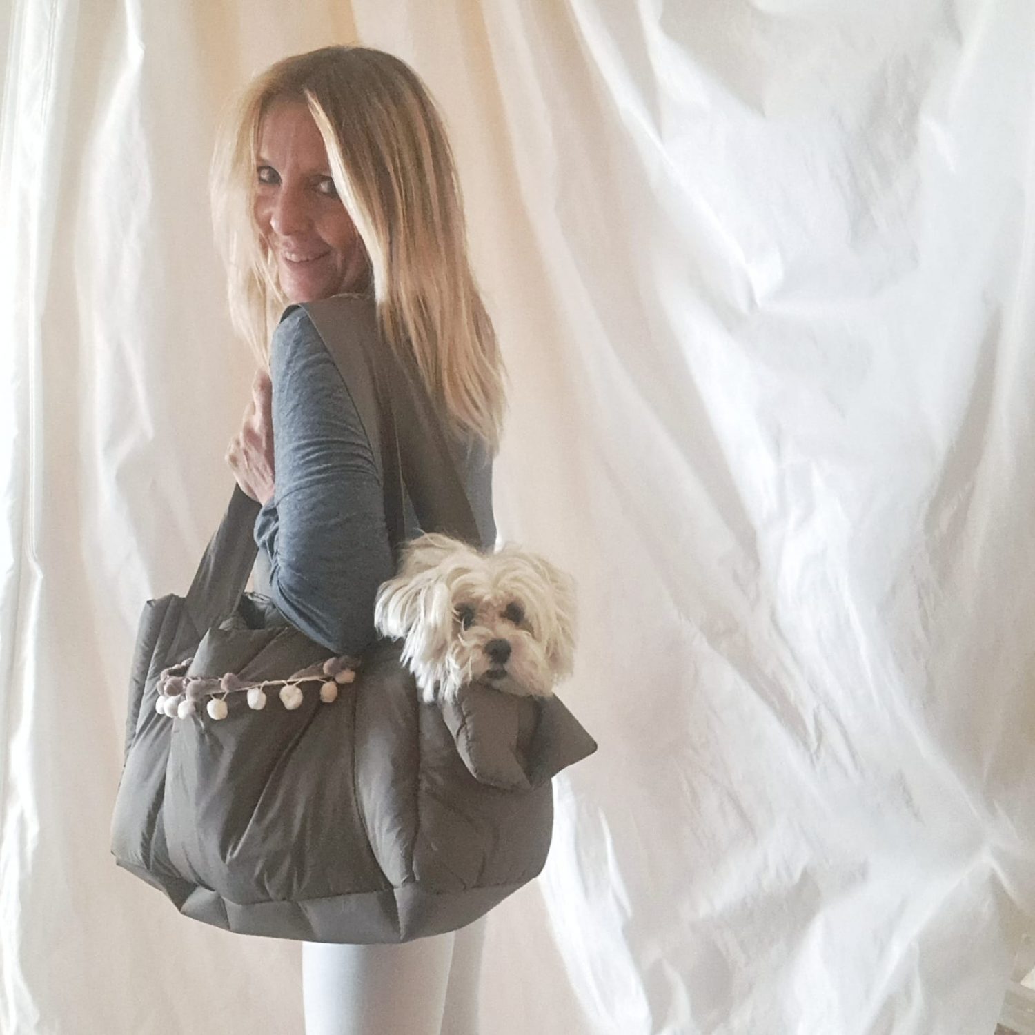 Noi andiamo! Olga sei pronta? Piccoletti, non rimanete a casa ….la pioggia non sarà più un problema! Baisesmamain - Cecilia Benetti Design -Doggy Rainy Bag - borsa impermeabile per cani piccola taglia donna indossa borsa impermeabile con cane seduto dentro